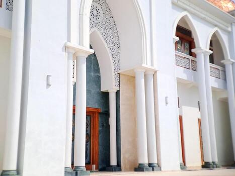 Facade of a building featuring white arches, columns, and intricate geometric patterns in daylight. photo