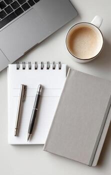 Laptop, notebook, notepad, pens and coffee cup arranged on white table photo