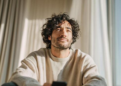 Man contemplating, looking up, enjoying sunlight indoors photo