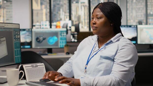 retrato de sonriente ingeniero utilizando ordenador personal a crear solar motorizado dispositivo diseño con limpiar energía tecnología. contento africano americano mujer en rd oficina creando eco solar artilugio prototipo, cámara si foto