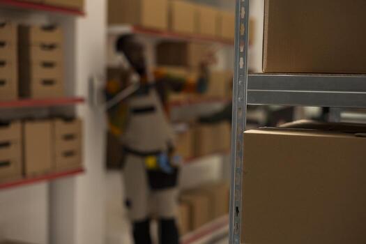 Out of focus shot of african american worker answering dispatch call on phone in a small scale depot, discuss shipping operations and cargo handling. Distribution for e-business online shopping. photo