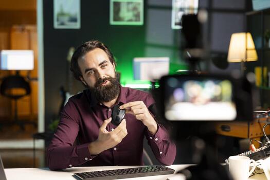 Tech guru filming technology review of office mouse for audience using professional camera. Content creator assessing computer peripheral device, recording with specialized equipment photo