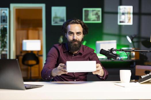 Tech expert filming technology review of newly launched cellphone, doing unboxing and presenting specifications to audience. Vlogger showing mobile phone box to subscribers photo