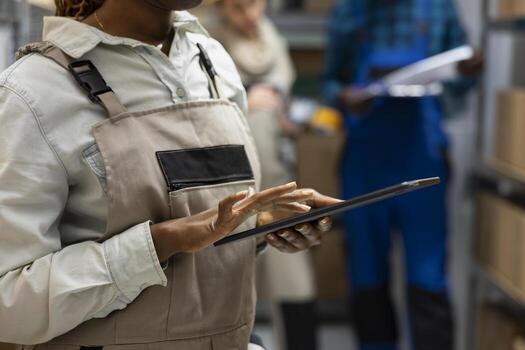 Black worker in safety gear performing essential tasks in the warehouse, managing bar code scanning, crate stacking and cargo dispatch as part of a industrial logistics center operations. photo