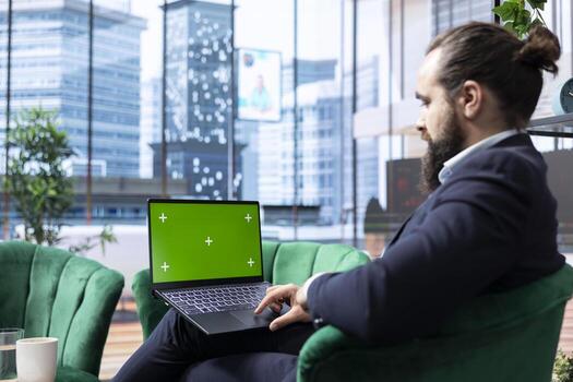 Determined executive administrator uses device with copy space screen, tracking profit margins and making data driven decisions. Young entrepreneur working on a success story, multitasking. photo