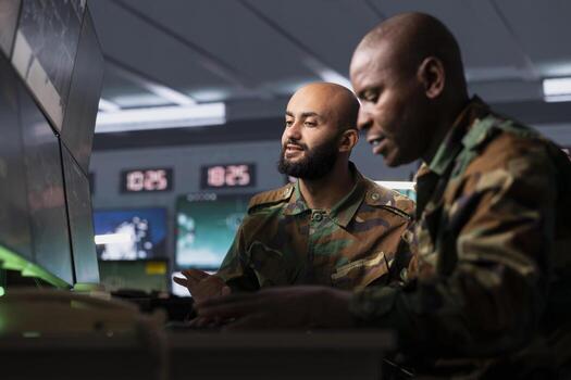 Military team conducts tactical reconnaissance in command center, utilizing devices for data analysis. Soldier and coworker use satellite technology to look at aerial map, pinpointing targets photo