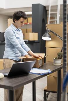 Warehouse employee managing factory operations in a local storage room, processing orders and handling packages to ensure efficient distribution of merchandise. Small business. photo