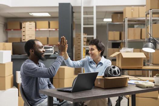 Diverse staff members expressing happiness with a high five in shipping area, representing the success of small business operations and order processing. Small scale delivery services. photo