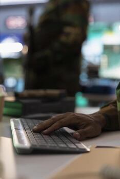 Army officer typing on keyboard, using surveillance equipment to do threat monitoring and target recognition. Military expert doing computer programming, employing modern warfare intelligence photo