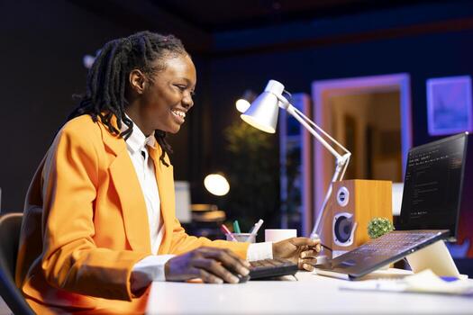 Cheerful engineer writes code on laptop while in apartment office, feeling excited after being successful. Overjoyed programmer celebrating fixing database errors while working from home photo