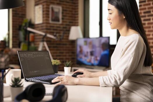 Remote software developer working on laptop, typing in programming language for startup project. Young female IT expert seated at desk, managing web development from cozy home. photo