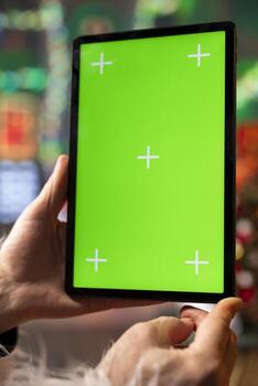 Close up of Santa Claus typing on mockup tablet touchscreen to reply to Christmas requests sent online by children. Saint Nicholas looking at green screen device display to check email inbox photo