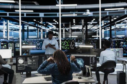 Fatigued data center worker stretching at desk, using machine learning algorithms to analyze datasets. Tired server farm engineer relaxing muscles, using AI to recognize data patterns photo