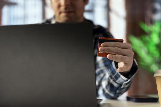 Man doing internet shopping, typing credit card information on notebook, placing products in cart. Close up of buyer doing online transactions, adding payment method on website photo