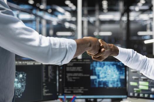 Data center colleagues fist bumping, saluting each other, using deep learning algorithms to analyze datasets. Server farm coworkers doing greeting hand gesture, using AI to recognize data patterns photo