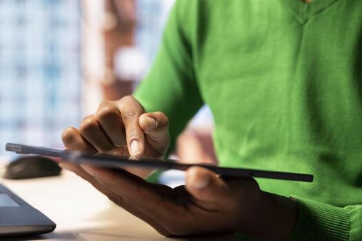 Man at home browsing internet, typing on digital tablet touchscreen, researching information online. Person in living room using device to find relevant info, close up shot photo
