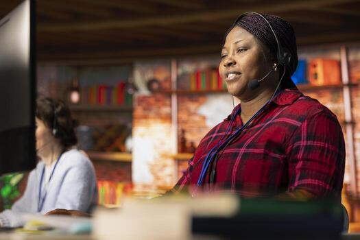 Smiling call center worker using headset microphone to answer customers technical inquiries about hardware issue. Happy woman doing customer support job using PC to troubleshoot problems photo