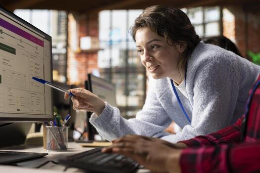 Smiling call center onboarding specialist teaching worker how to track lost shipments in office. Friendly customer center manager showing employee how to use software to locate clients packages photo