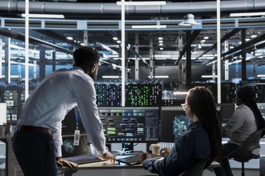 Data center manager supervises engineer using AI visual programming to optimize gear. Server farm team leader overseeing work done by worker colleagues using artificial intelligence analysis software photo