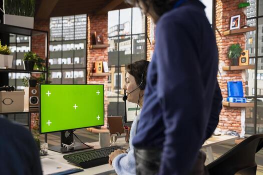 Call center agent using remote access tools on green screen PC to connect to customer devices, fixing errors. Worker in customer center using chroma key computer, installing software for clients photo