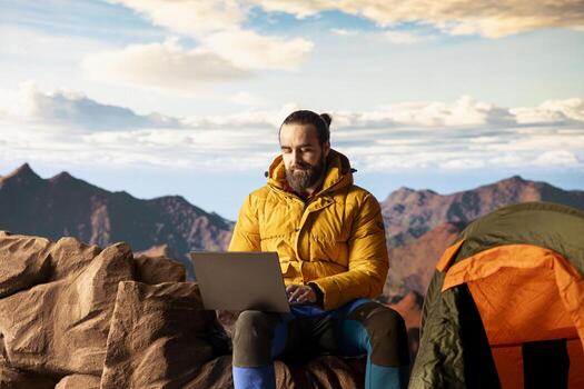 Hiker with a technology obsession and strong signal working in nature, climbing the top of the mountain and connecting to work platform. Workaholic person enjoying internet everywhere. photo