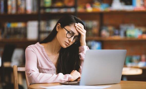 Disappointed arab lady using laptop and having problems, working on computer remotely in cafe, suffering from headache and emotionally reacting to business troubles, free space photo