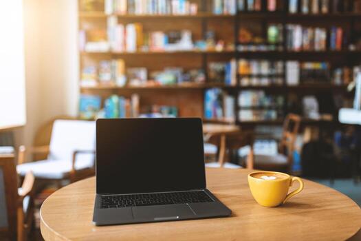 Workplace in cafe. Laptop computer with black blank screen and mug of coffee on wooden table. Notebook screen with copy space for your content. Mockup, empty space photo
