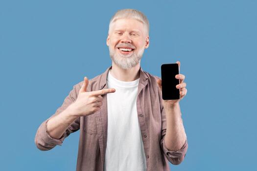 Check this app. Joyful albino guy holding cellphone and pointing finger at smartphone with black screen, studio background with free space. Mockup for mobile application or website photo
