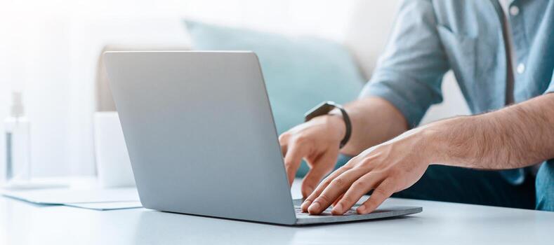 Unrecognizable bearded man working on pc, typing text or programming code on computer keyboard, sittng on sofa at home, cropped, empty space. Busy male entrepreneur photo