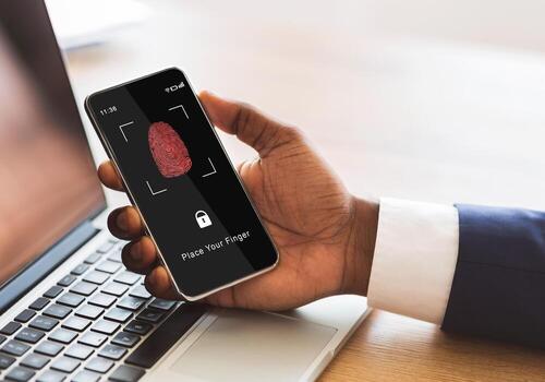Biometric Identification Concept. African American Man Holding Cellphone In Hand, Showing Application For Fingerprint Scanning With A Zone To Touch With Thumbprint Icon On The Device Screen photo