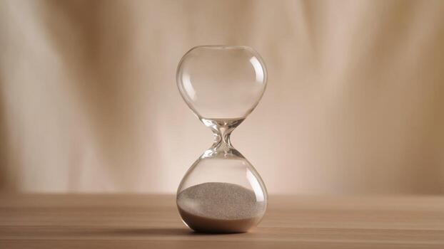 A simple hourglass on a wooden table with a beige backdrop, symbolizing time flow and minimalistic living. Represents timeless themes in a creative, uncluttered presentation for stylish concepts n photo