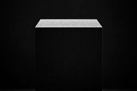 Minimalist black cube on dark background with textured top photo
