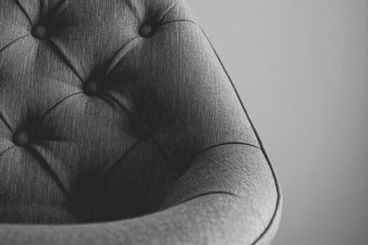 Modern fabric chair with tufted design in grayscale setting photo