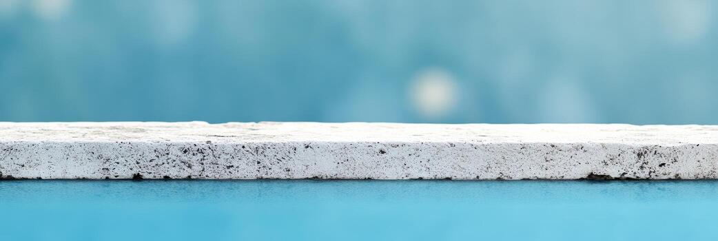 Calm blue background with a textured white ledge at sunset photo