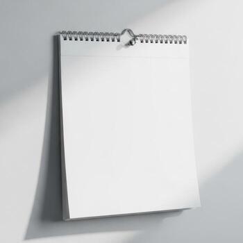 Blank spiral bound calendar page hanging on a wall with soft shadows isolated on white background photo