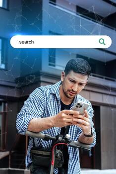 Young man using smartphone while standing on scooter in front of modern building during daytime photo