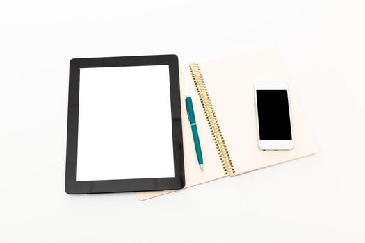 Workspace setup with tablet, notebook, pen, and smartphone displayed on white background photo