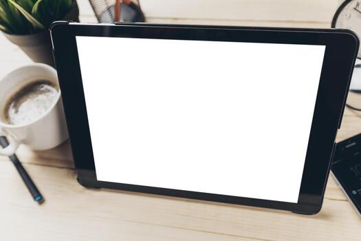 Table setup featuring a tablet, coffee cup, and stationery in a cozy workspace photo