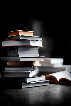 Stack of various books on a dark surface in a cozy reading space during evening hours photo
