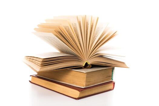 Stacked books with an open book displaying fanned pages and a soft light background photo
