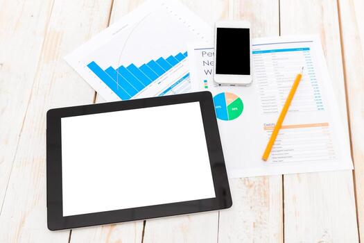 Digital workspace setup for data analysis with tablet and documents on wooden table photo