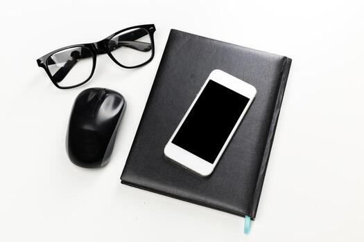 Workstation setup with glasses, notebook, smartphone, and computer mouse for productivity photo