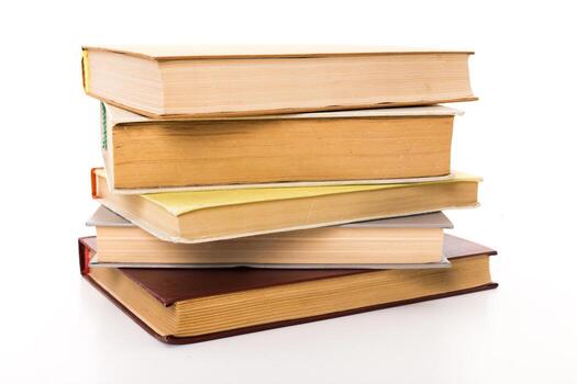 Stack of colorful books resting on a white surface with varied textures and colors photo