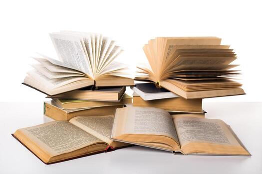 Stacked books with open pages showcasing various texts in a bright setting photo