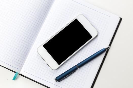 Notebook with a smartphone and pen resting on an open page in a workspace photo