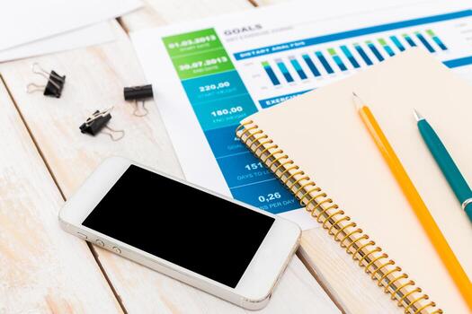 Organizing tasks and tracking goals on a workspace with a mobile device and stationery photo