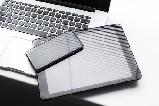 Devices resting on a modern workspace with shadows casting over them photo