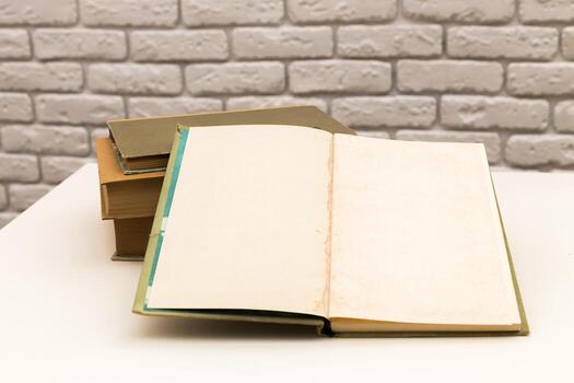 Old books stacked with an open notebook on a table in a cozy room setting photo