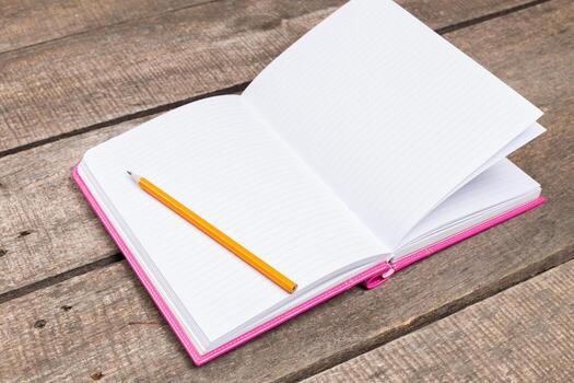Open notebook with a pencil resting on wooden table during a calm study session photo