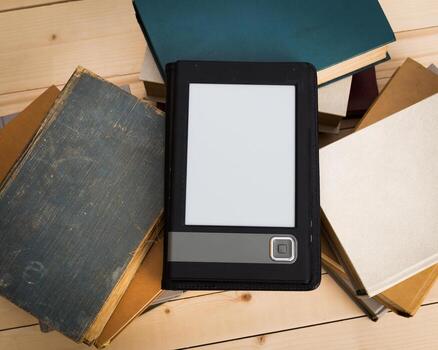 E-reader resting on a stack of old books in a cozy reading nook photo